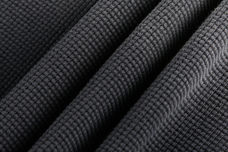 Close-up of ribbed waffle knit fabric folds in dark gray and black