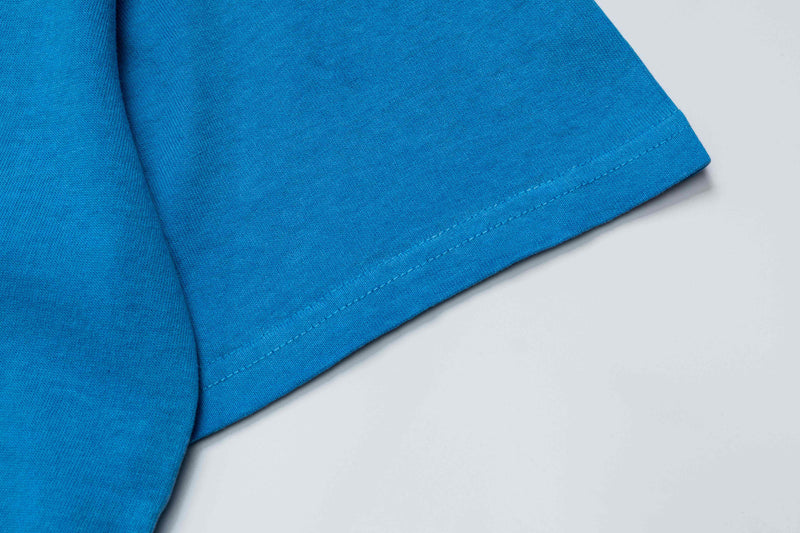 Close-up of a bright blue oversized cotton T-shirt sleeve with visible stitched hem on a white background