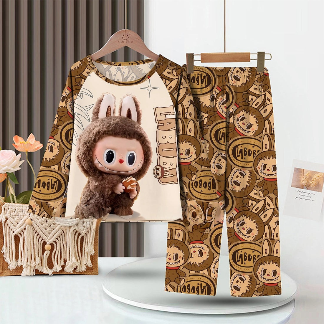 The LABUBU Baby Pajama Set is adorable sleepwear for kids, featuring a cute cartoon character in a brown animal costume on both the top and pants. Made from soft milk silk fabric, it&