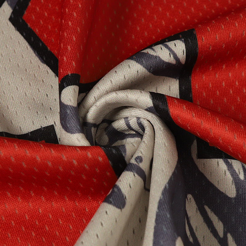 Close-up of red and cream mesh football jersey fabric with bold black butterfly graphic detail