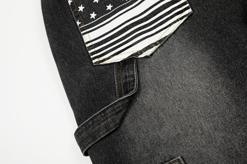 Close-up of pocket flap with star print and striped trim on black denim pants