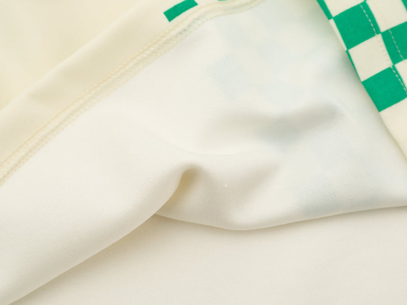 Close-up of cream jersey side seam and green checkered print