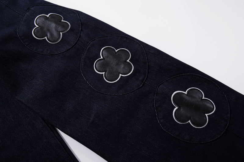Three floral patches on dark wash denim leg, close-up detail