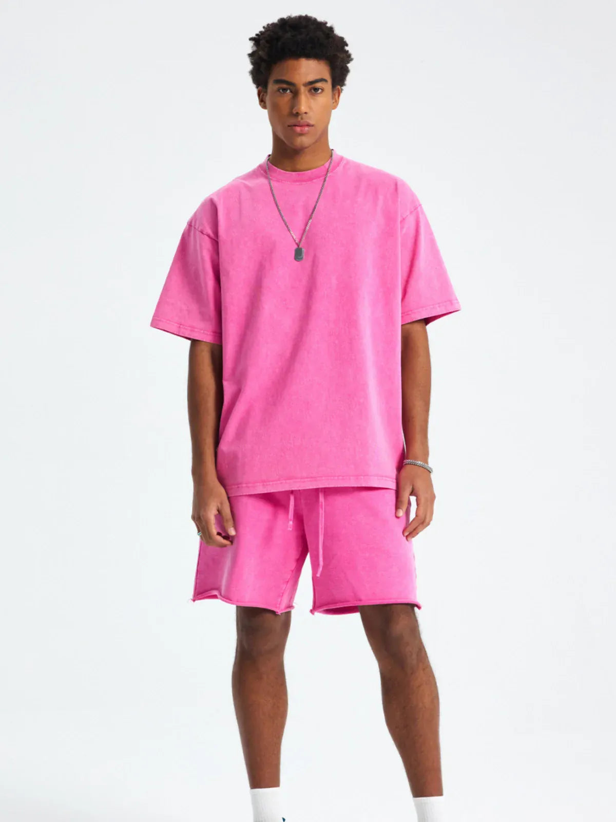 A man stands facing forward, wearing a Custom Anime Character Pink Washed T-Shirt - Personalized Anime Style Tee and matching pink shorts, with white socks and sneakers, against a plain light background.