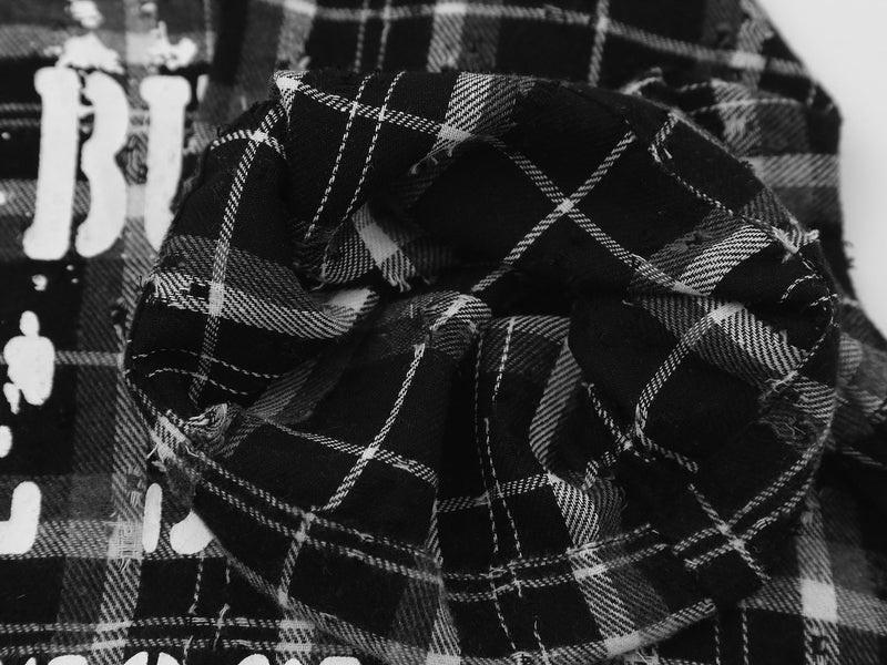 Black plaid streetwear shirt with frayed fabric details and bold Burn The Script graphic print close-up