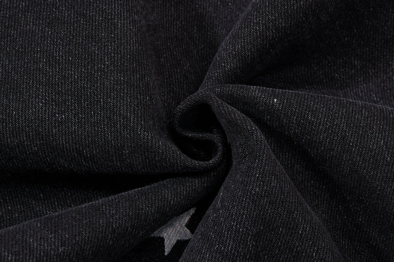 Close-up of black denim fabric texture with a small star print
