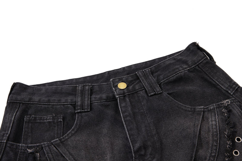 Close-up of black denim waistband and front pocket area with gold button and raw edge detailing