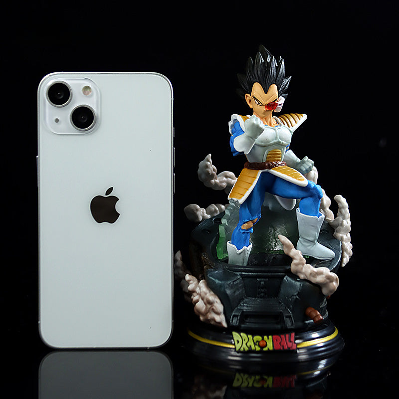 A Seakoff Dragon Ball Z collectible figure stands in blue and white armor with a smoke-effect base. The 17cm figurine, part of the Piccolo, Vegeta, and Cell set, is beside an upright Apple smartphone.