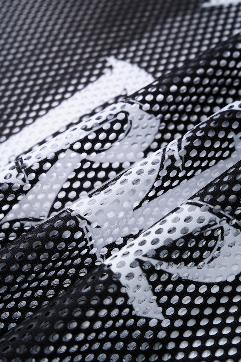Close-up of black and white mesh soccer jersey fabric with raised perforated texture and bold graphic pattern