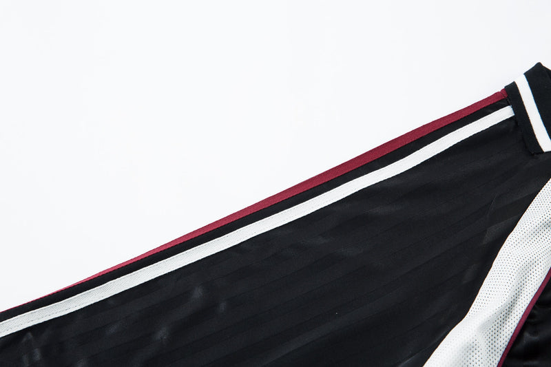 Close-up of black shoulder seam with white stripe and burgundy edge trim
