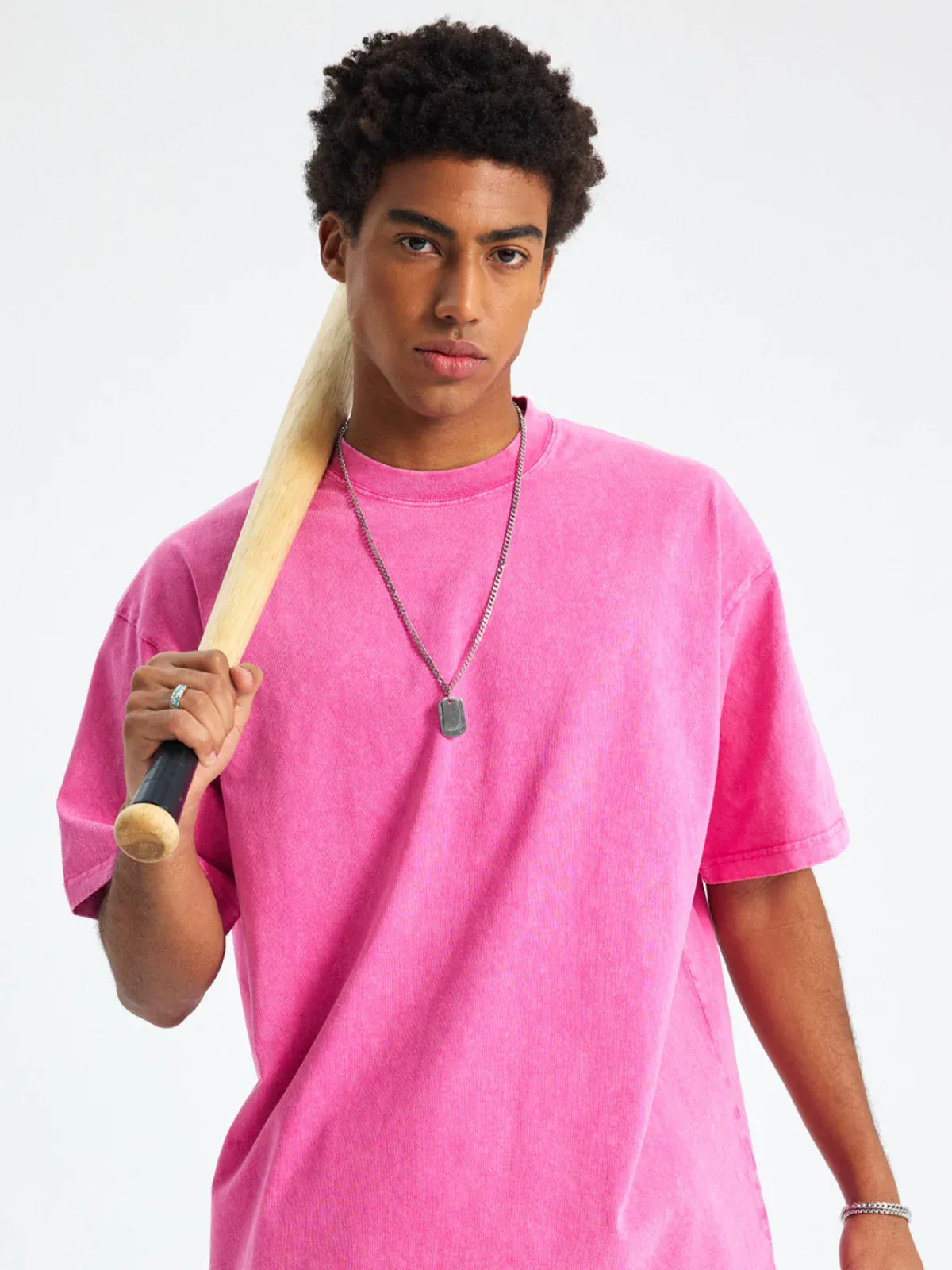 A young man in a Custom Anime Character Pink Washed T-Shirt - Personalized Anime Style Tee and necklace holds a wooden baseball bat on his shoulder, standing against a plain background.