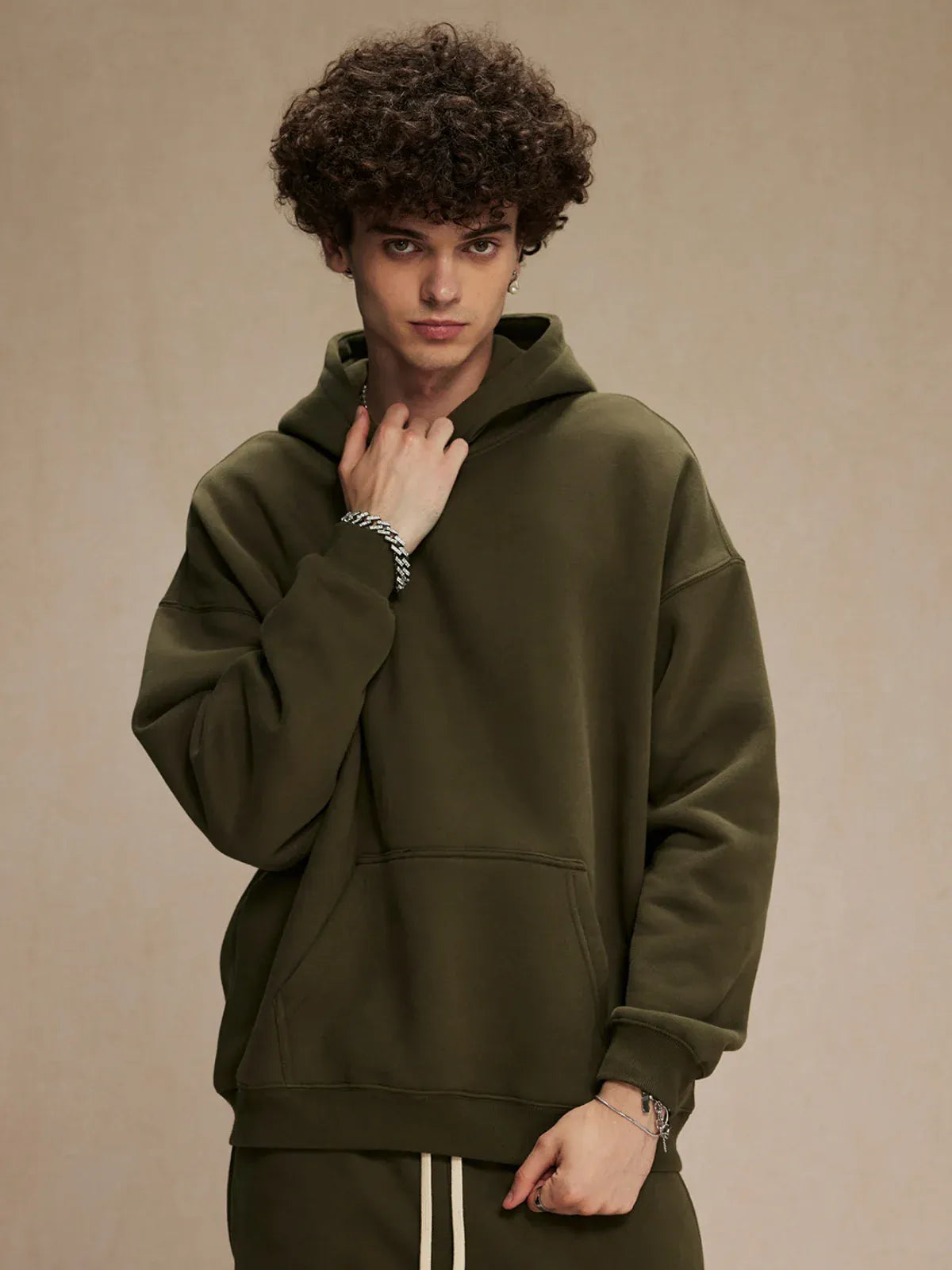 A person with curly hair wears a Custom Anime Character Olive Green Hoodie—Personalized 350GSM 100% Cotton Pullover—paired with matching pants, standing against a plain beige background.
