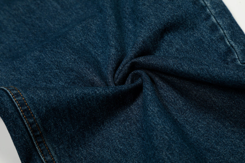 Close-up of dark indigo denim fabric folded to show texture and stitching