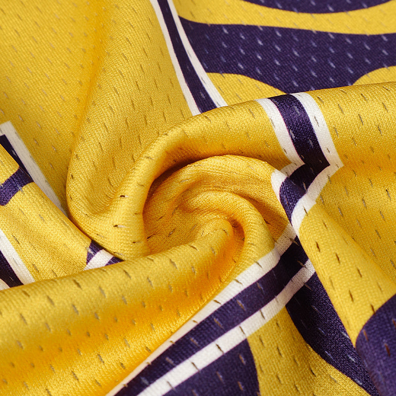 Close-up of a yellow and purple football jersey fabric with swirling varsity-style stripes and textured mesh detail
