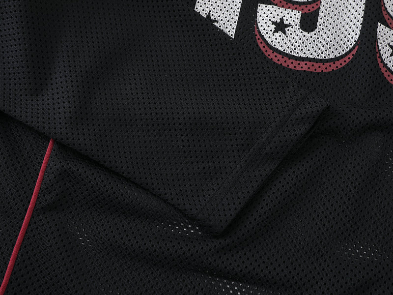 Close-up of black mesh shirt fabric and seam with red piping detail