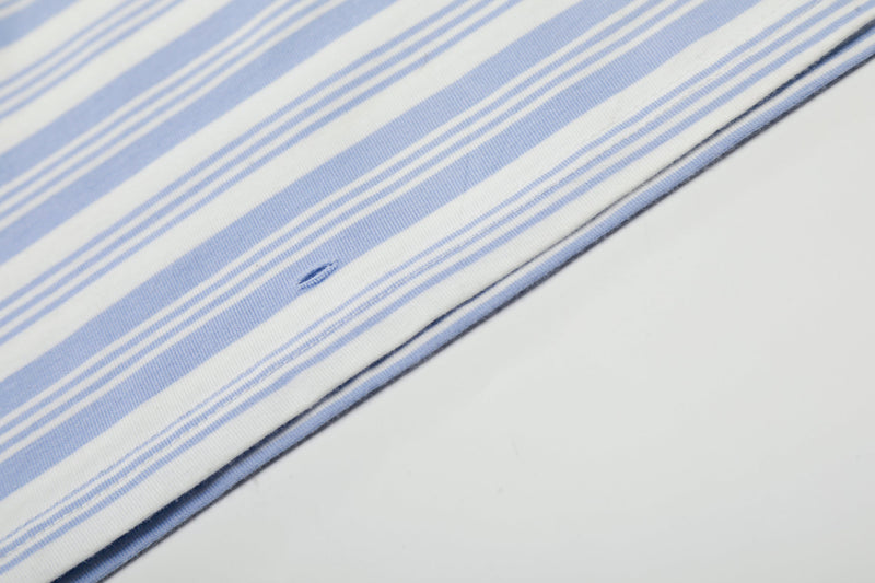 Close-up of striped hem and side seam on light blue polo shirt