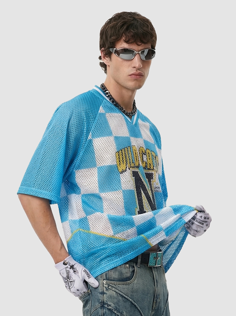 Model wearing a blue checkerboard mesh jersey T-shirt with Wild Cats N League graphic, sunglasses and gloves