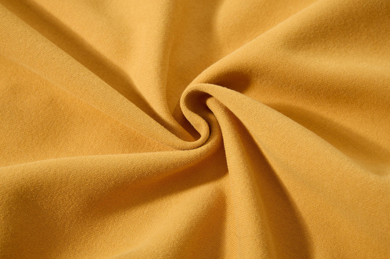 Close-up of mustard yellow fleece fabric with soft folded texture