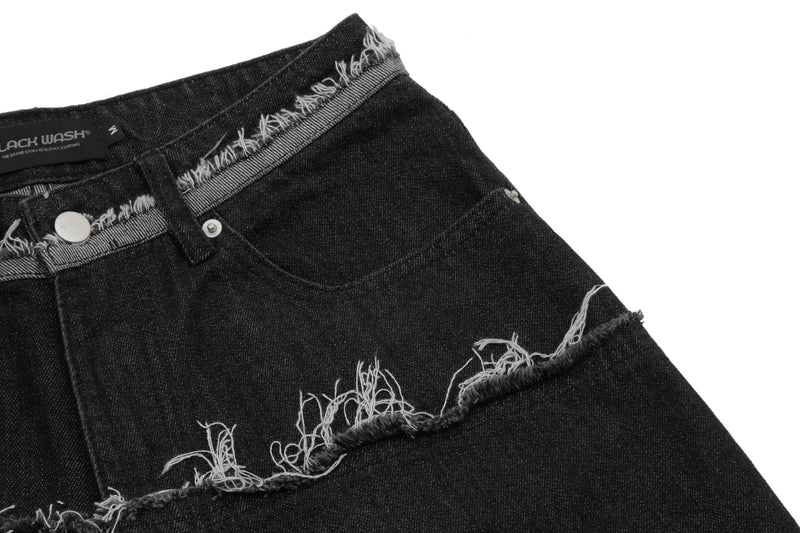 Close-up of black denim shorts front with frayed seam band and raw hem cuff detail