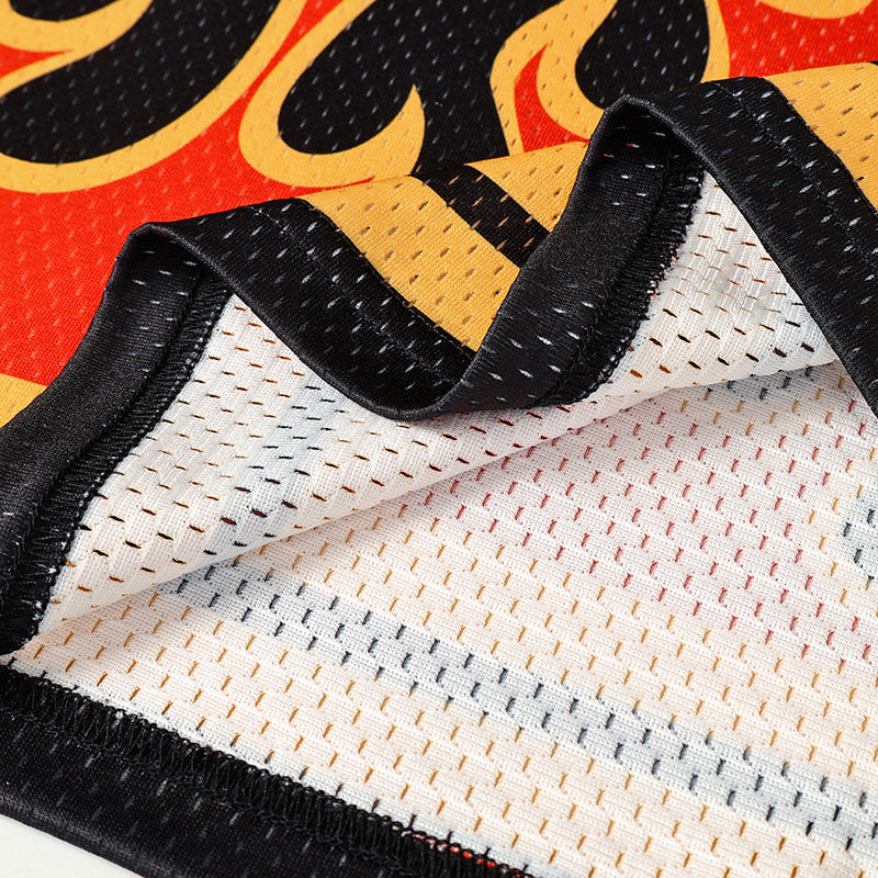 Close-up of a flame graphic football jersey in black and red mesh with gold varsity-style details and stitched trim