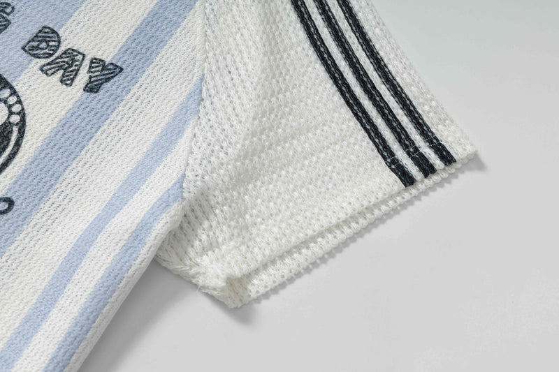 White knit rugby tee with light blue stripes, black sleeve stripes, and Good Dog graphic detail