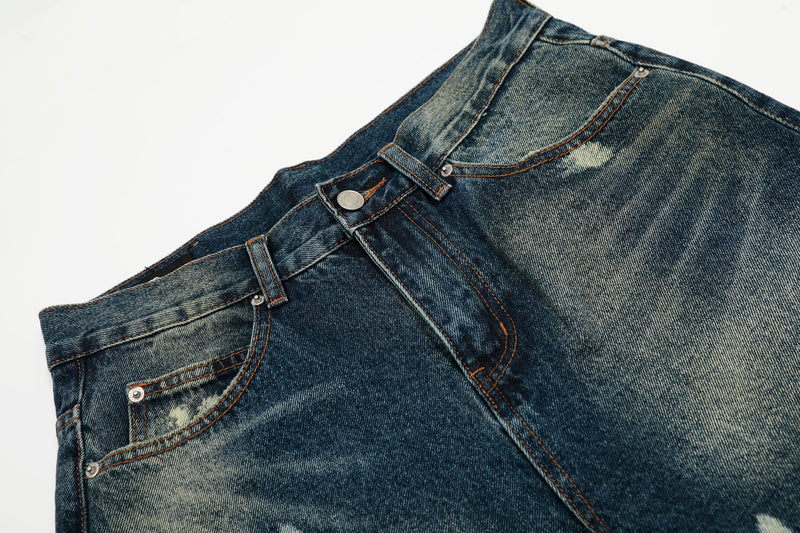 Close-up of the front waistband and pockets on dark wash paint-splatter jeans