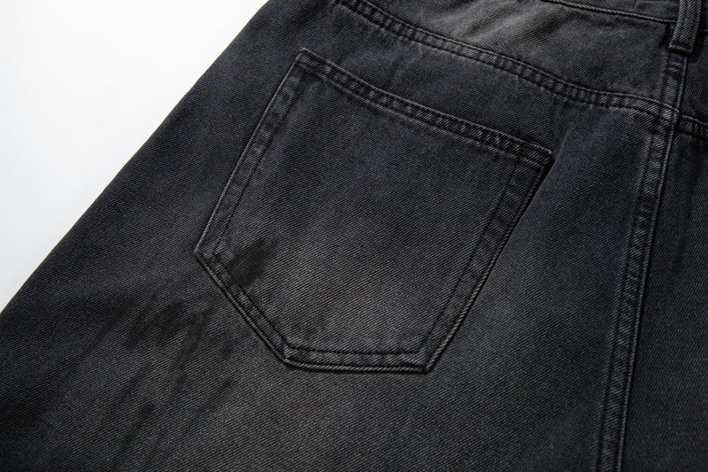 Close-up of back pocket on black shadow wash denim with faded worn texture
