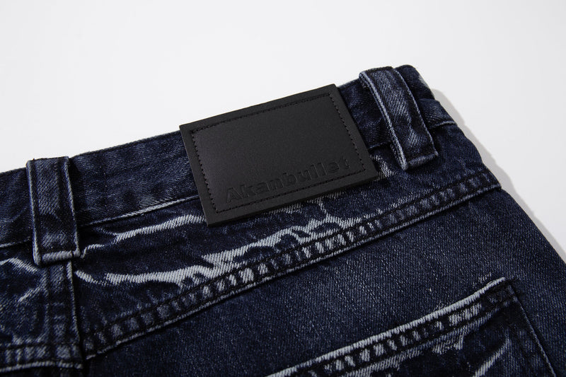 Close-up of the back waistband on deep indigo jeans with black logo patch and belt loops