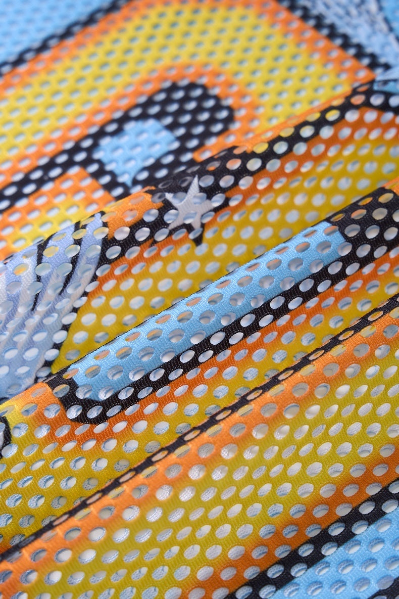 Close-up of colorful perforated mesh jersey fabric with orange, yellow, blue, and black striped streetwear design