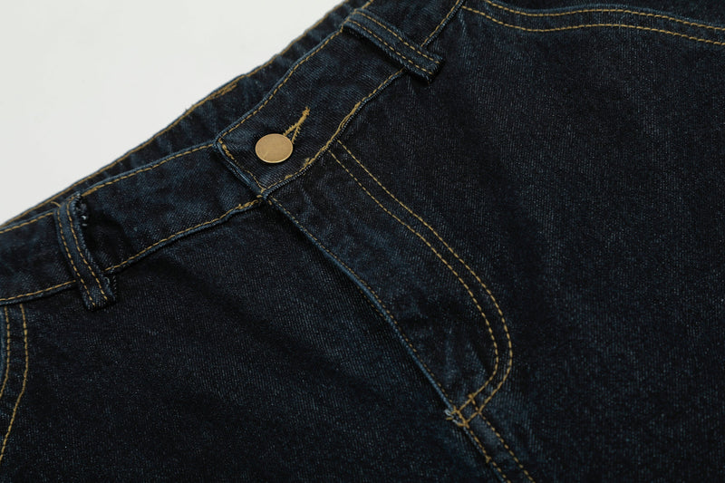 Close-up of front waistband button and curved seam stitching on dark wash denim pants