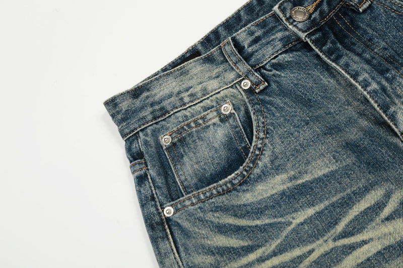 Close-up of front pocket and waistband detailing on faded distressed denim jeans