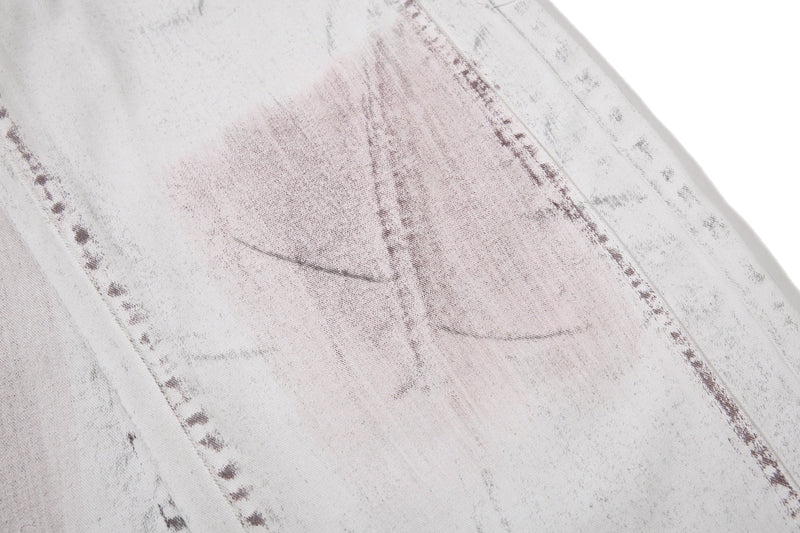 Close-up of washed denim panel seam with faded brown and gray markings