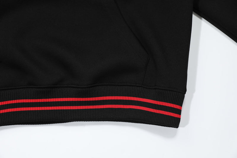 Close-up of black hoodie lower hem with ribbed red stripe trim