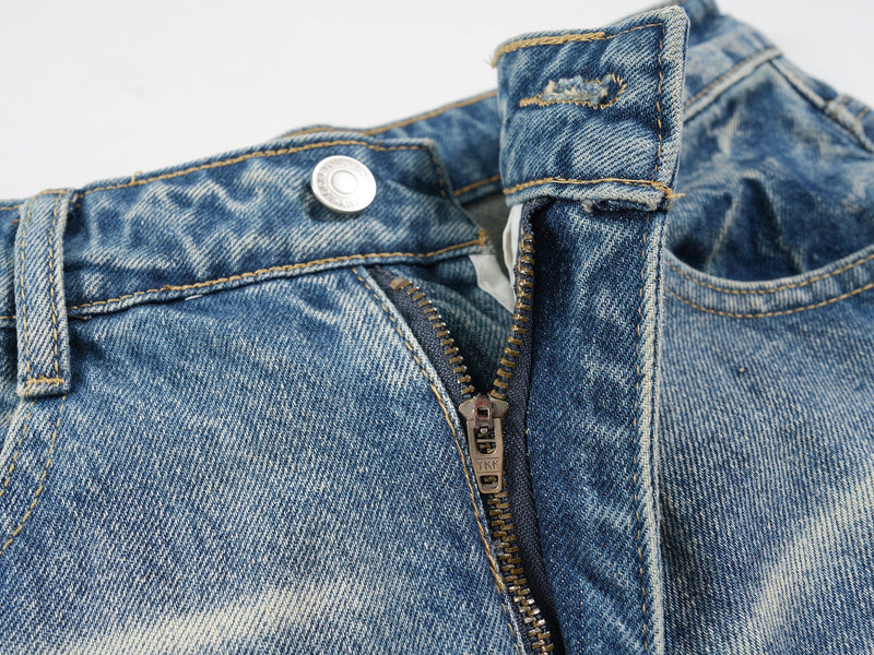 Close-up of the front zipper opening and waistband on blue denim shorts