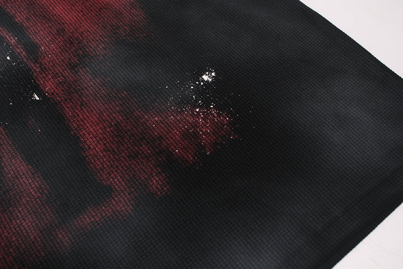 Close-up of black washed oversized tee with faded red shadow figure print and distressed speckled texture