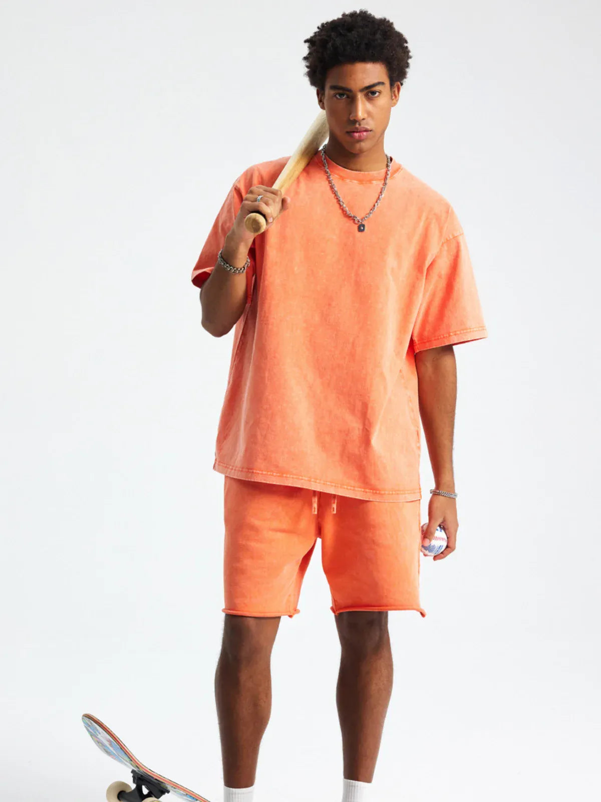 A person wears a Custom Anime Character Orange Washed T-Shirt - Personalized Anime Style Tee with matching shorts, holding a skateboard against a plain white background.