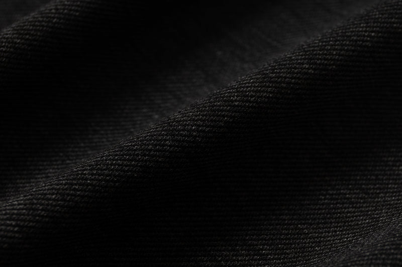 Close-up of black textured fabric with subtle diagonal folds, matching a gothic streetwear raglan T-shirt
