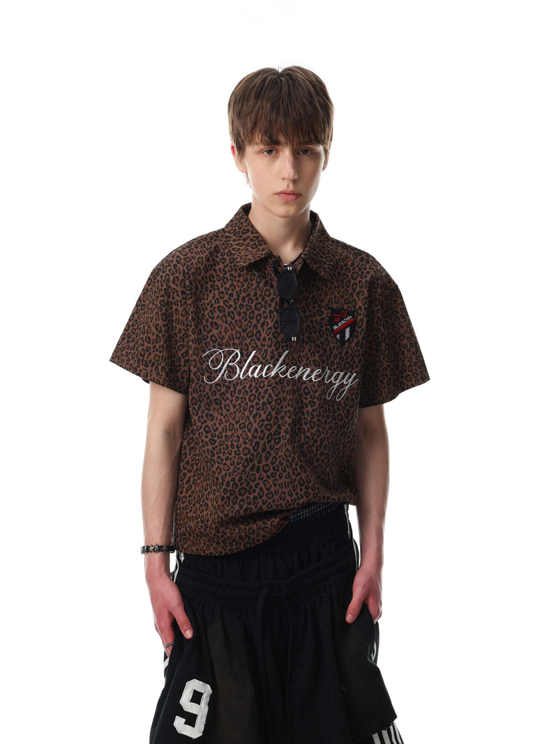 Brown leopard print polo shirt with white script logo and short sleeves, styled on a male model