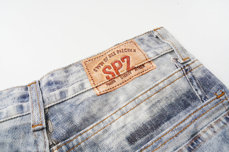 Close-up of the back waistband logo patch on faded patchwork jeans
