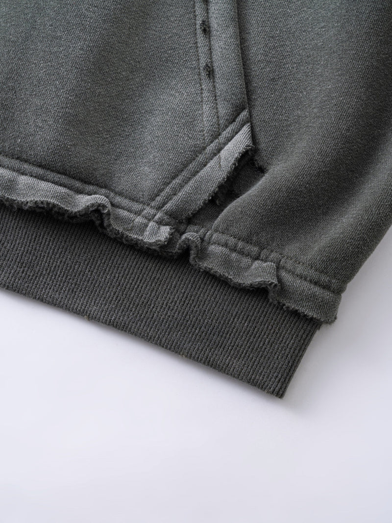 Close-up of gray hoodie hem and front pocket corner with raw edges