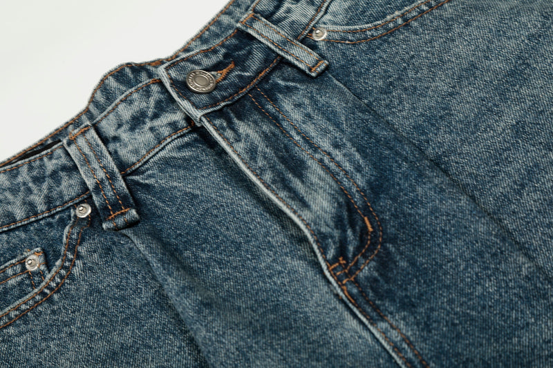 Close-up of front waistband showing button, belt loops, and faded denim texture