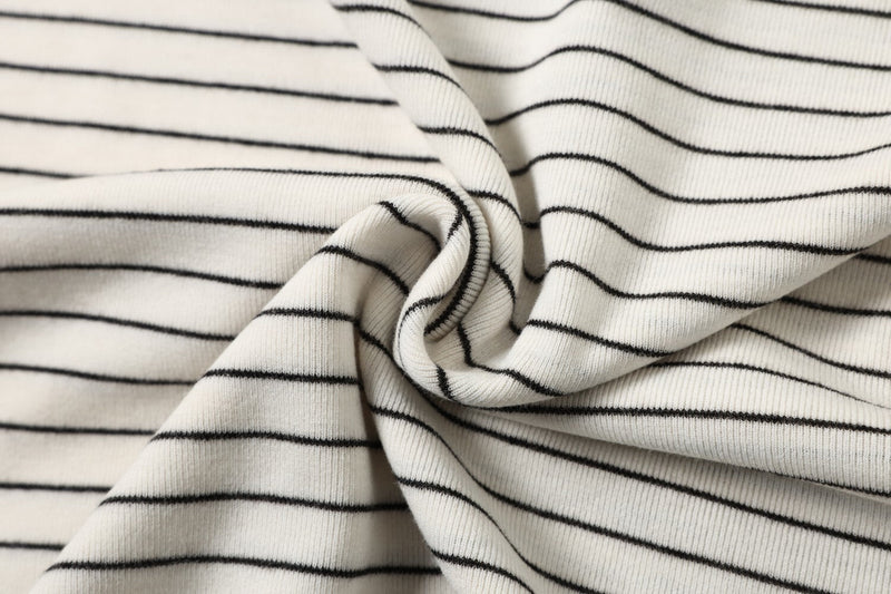 Close-up of white ribbed T-shirt fabric with thin black horizontal stripes and soft gathered folds