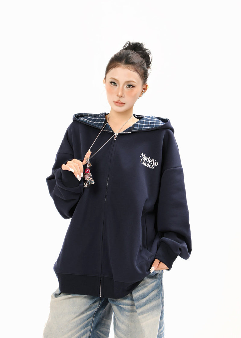 Model wearing a navy zip-up hoodie with blue plaid hood lining and front logo print