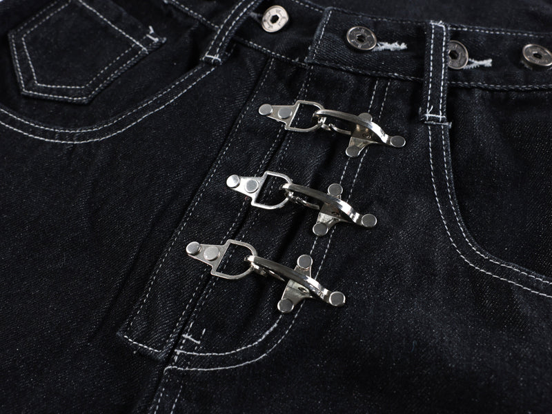 Close-up of three metal buckle closures on black denim jeans front