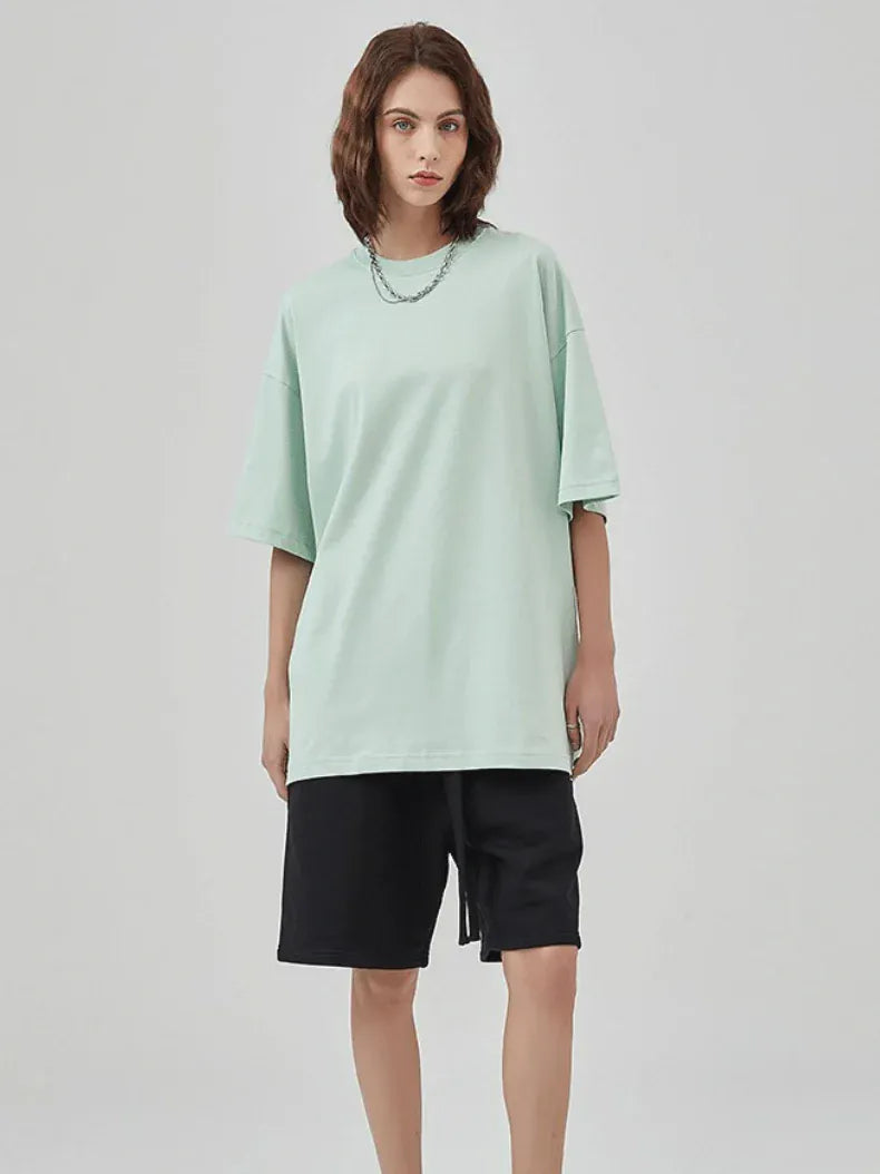 Person wearing a Custom Anime Character Mint Green T-Shirt - Personalized 230GSM 100% Cotton Tee, black knee-length shorts, and a chain necklace, standing against a plain light background.
