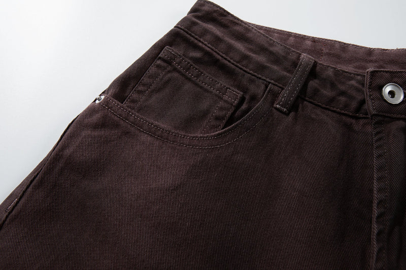 Close-up of the front left waistband and pocket on brown washed denim