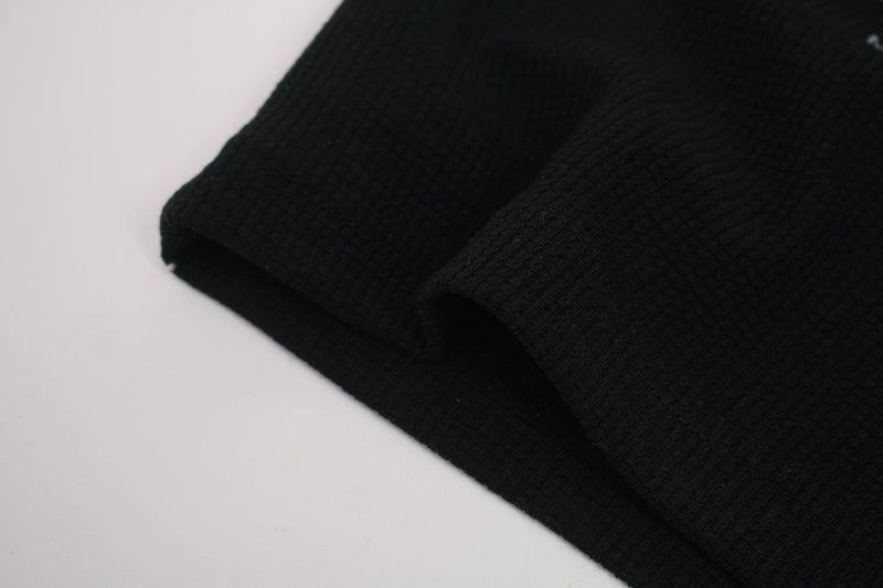 Black ribbed streetwear tee sleeve with a relaxed draped hem and textured knit fabric detail