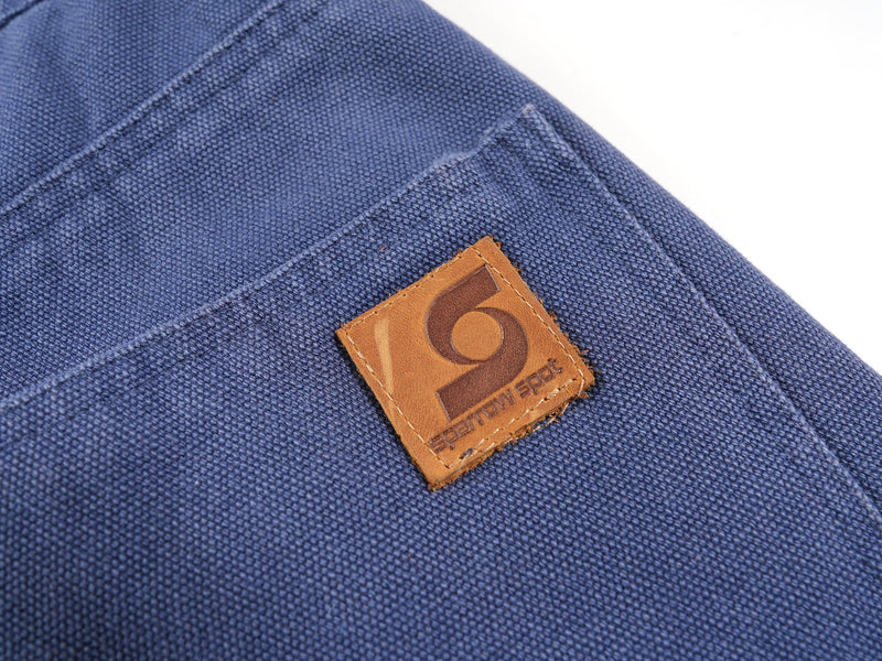 Close-up of brown logo patch on blue jorts back pocket