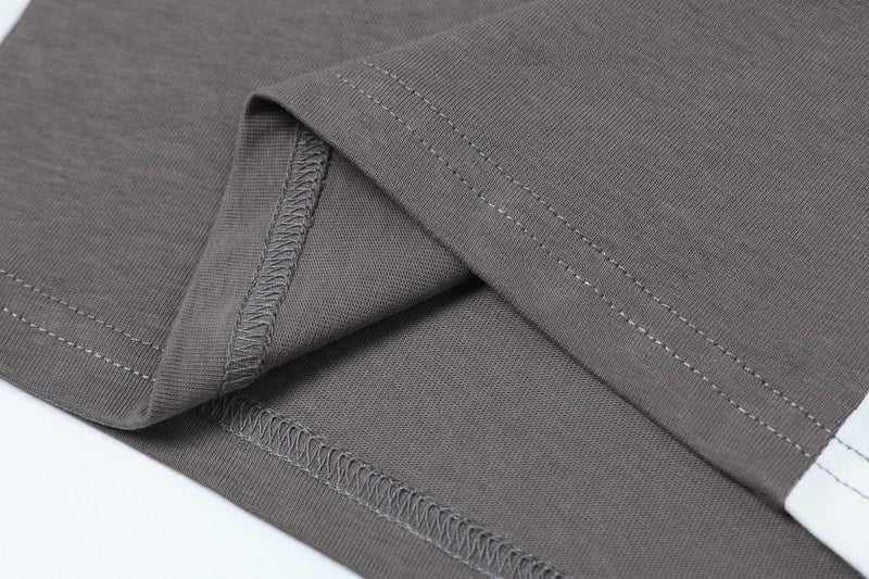 Close-up of a gray colorblock streetwear T-shirt with visible contrast stitching and hem detailing