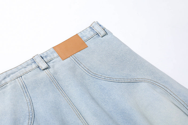 Close-up of back waistband on light wash jeans with tan patch and belt loops